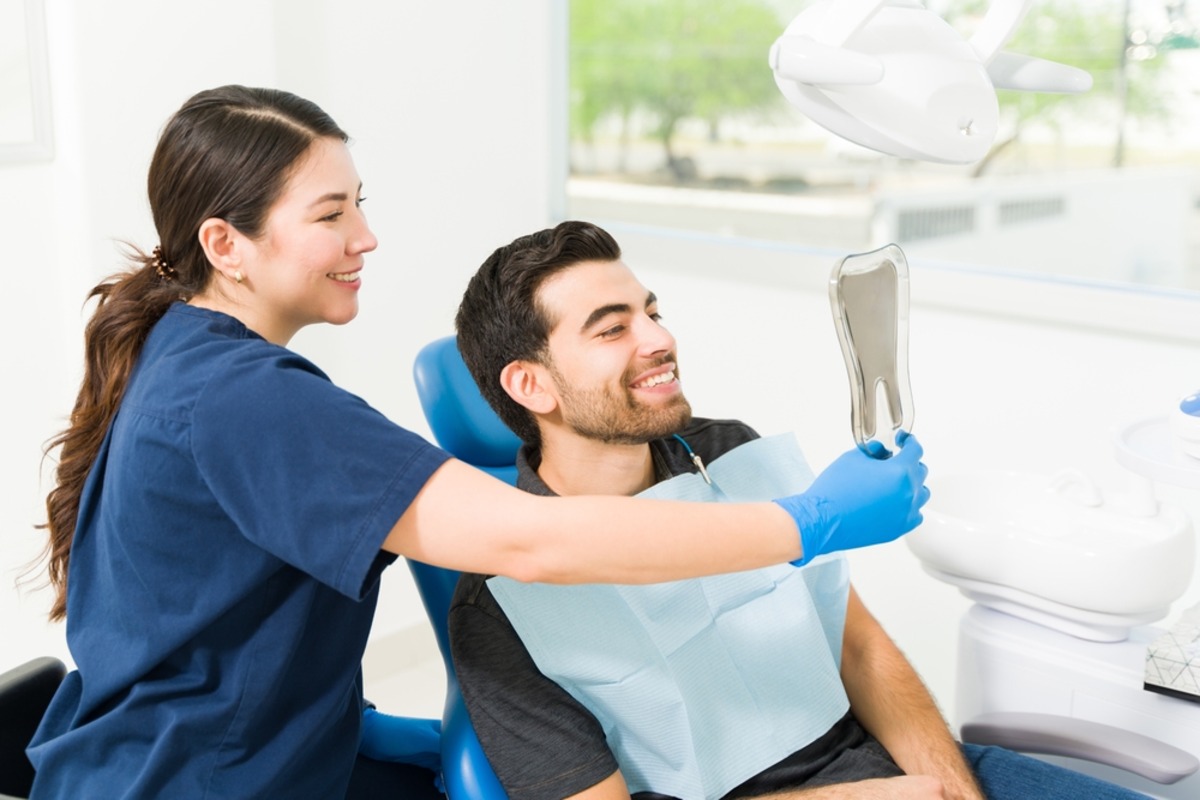 dentist showing patient smile dental mirror