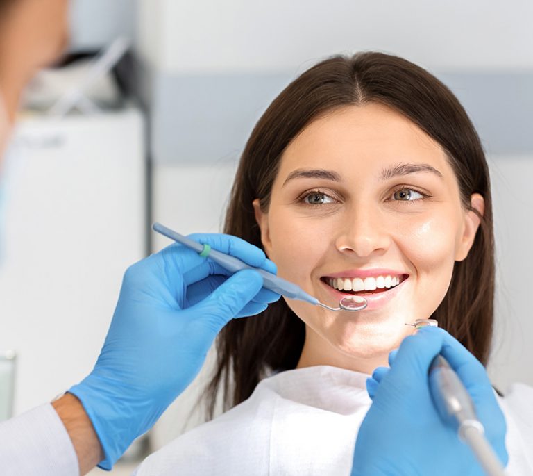 a lady is smiling while getting dental cleanings and checkups