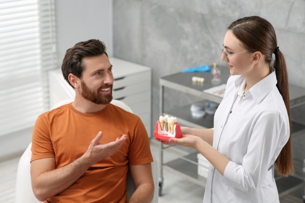 dentist explaining dental implant model patient